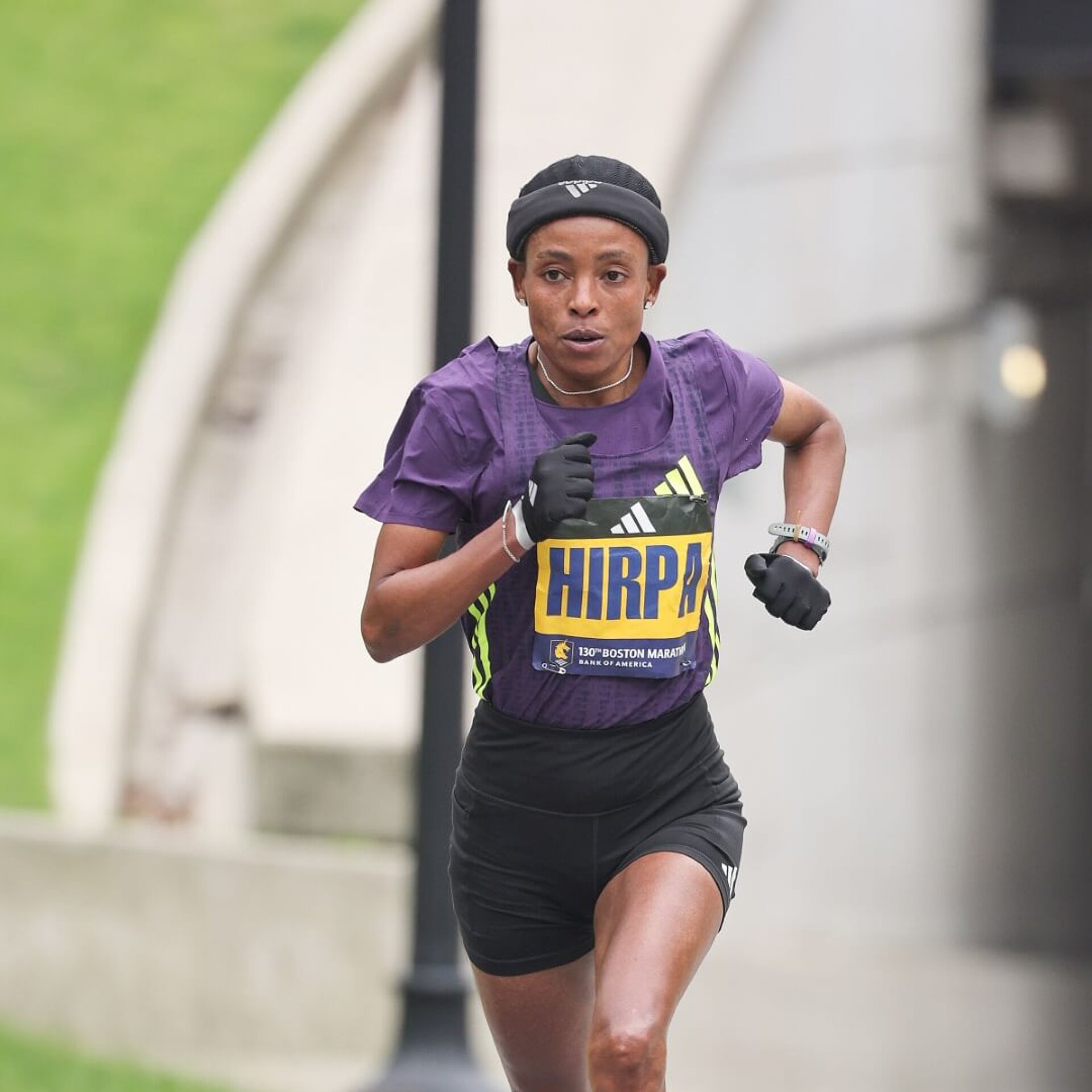 Bedatu Hirpa runs up a hill with determination in her face during the Boston Marathon.