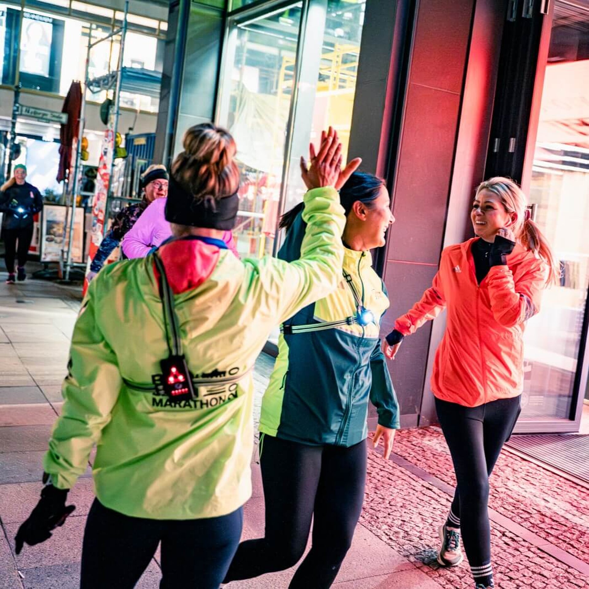 Zwei Teilnehmerinnen geben sich am Ziel ein High-Five, während eine dritte ankommt.