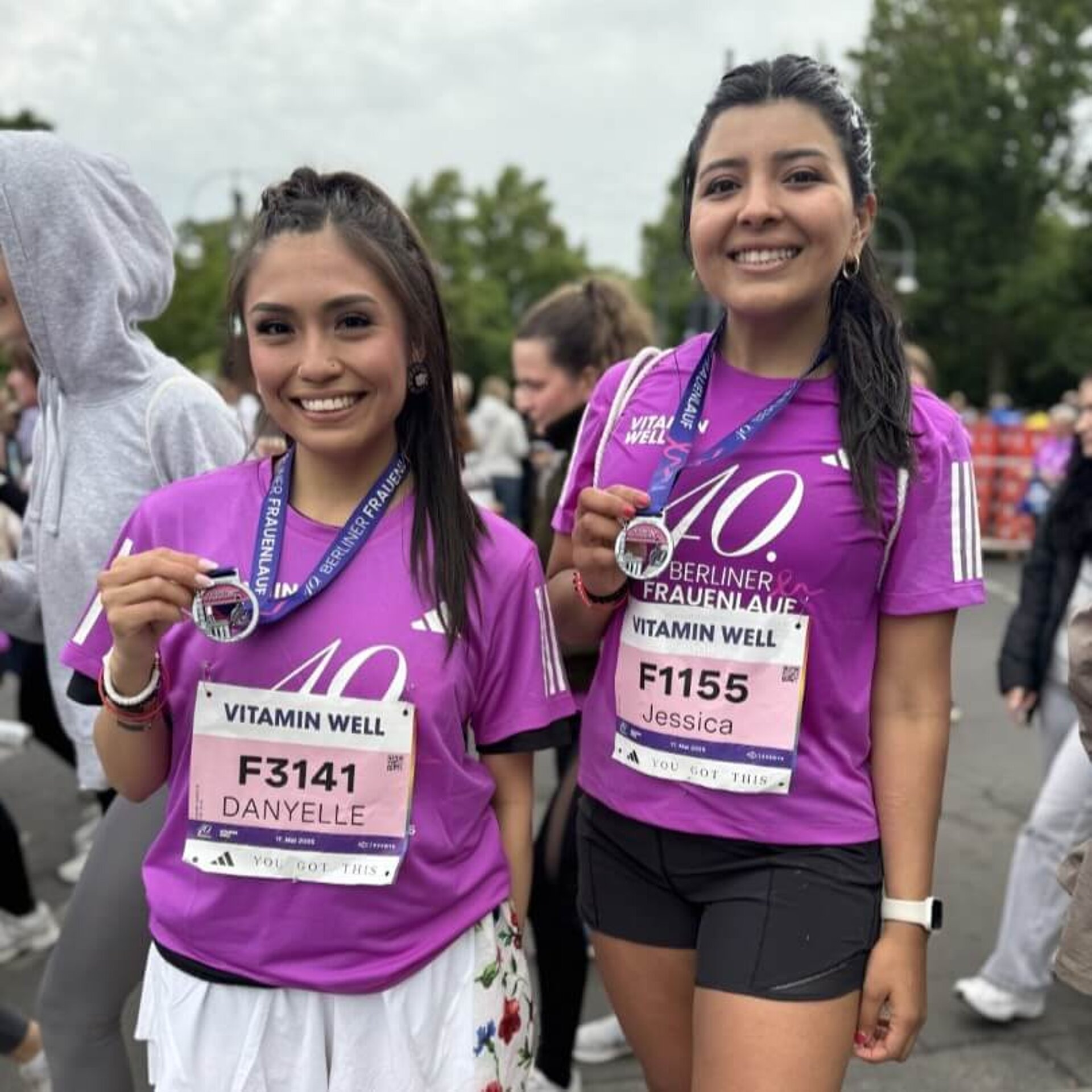 Dieselben Läuferinnen, die das Banner gehalten haben, zeigen glücklich ihre Medaillen.