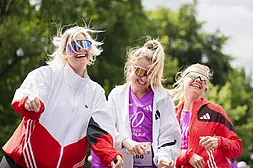 Drei lachende Frauen mit Sonnenbrillen beim VITAMIN WELL Frauenlauf Berlin.