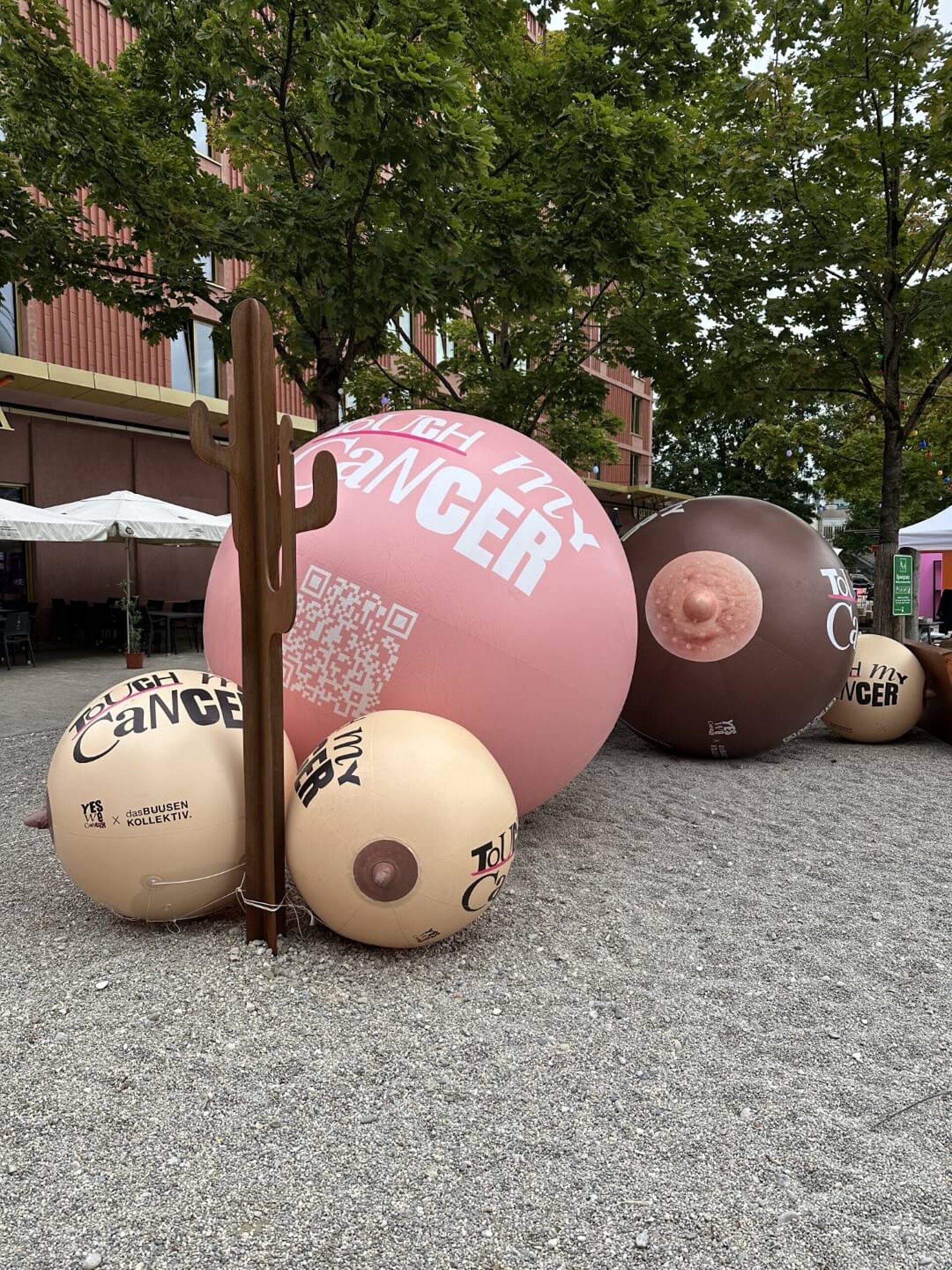 Verschiedenfarbige aufblasbare Gummibrüste mit Durchmessern von ca. 60 cm bis 2 m mit Beschriftung: "Touch my cancer".
