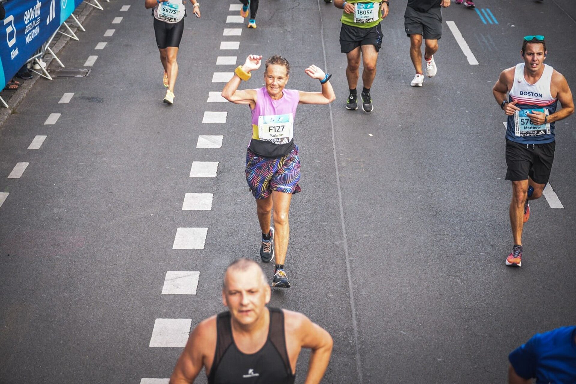 Sabine celebrates with her arms raised on the course of the BERLIN-MARATHON.