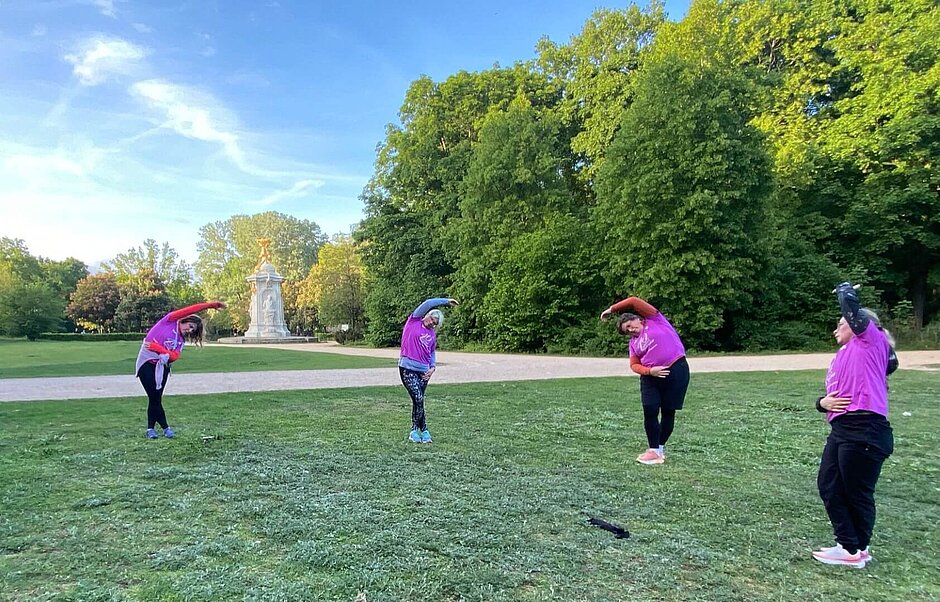 Women's race training group stretching together on a lawn.