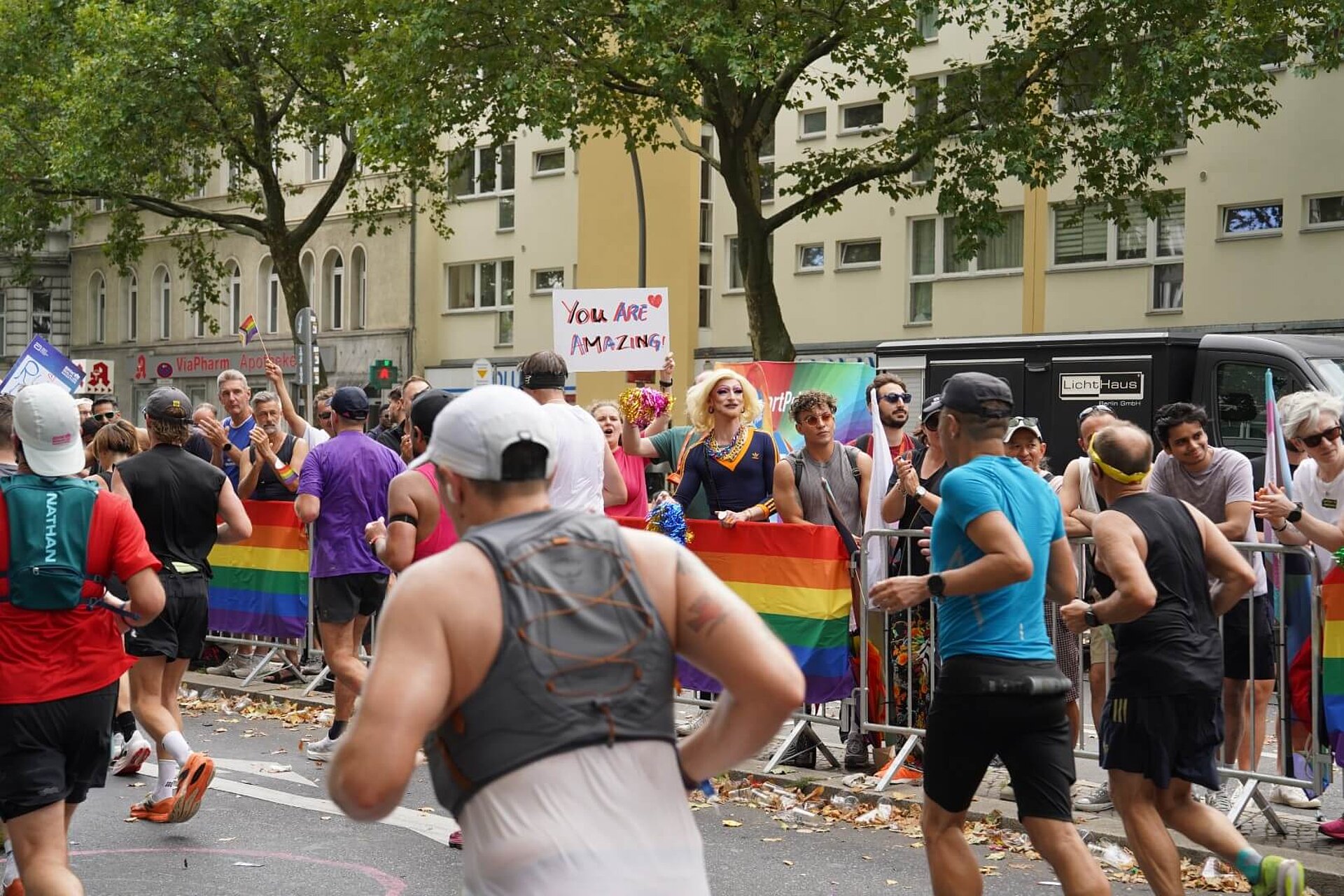 Queer Cheer, with rainbow flags lining the route and a person in drag.